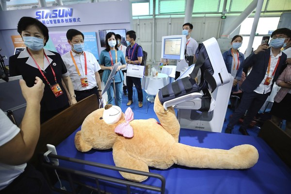 Visitors watch how a robot helps patients recover at the 2020 China International Fair for Trade in Services in Beijing on Saturday, Sept 5, 2020. [Photo by Zhang Wei/China Daily]