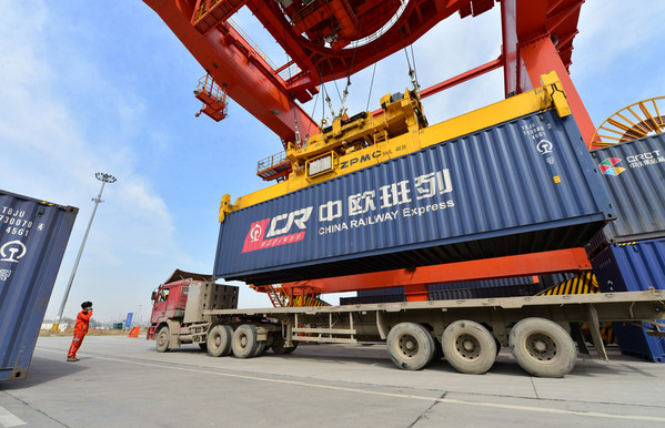 A worker directs container hoisting operation at a logistic station in Xinzhu Railway Station in Xi'an, March 11, 2020.