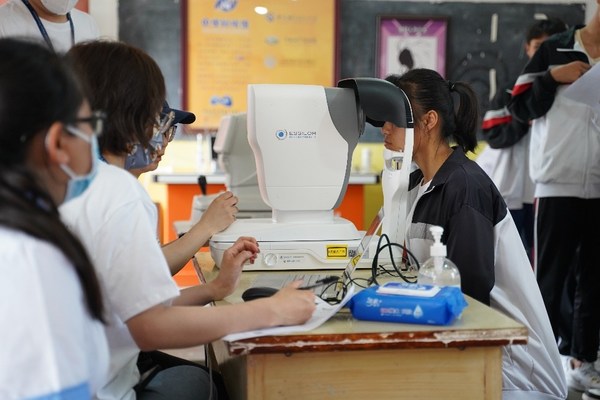 志愿者使用依视路光学生物测量仪为孩子测量眼轴