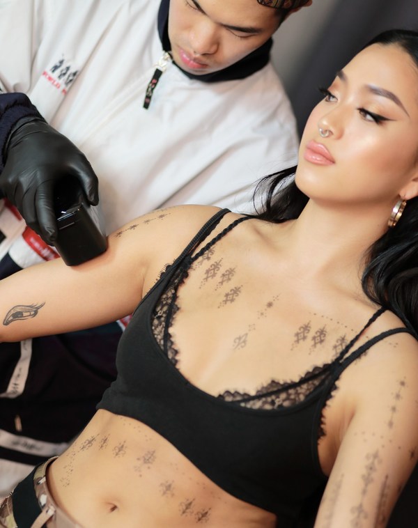 An Opium Studio tattoo artist using Prinker to apply a temporary tattoo on a model