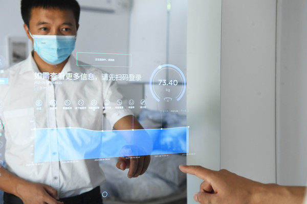 A man clicks the mirror to check his healthy status in the Chongqing Lijia Smart Park, where people can experience “A Day of The Smart Life”, as part of the exhibitions of Smart China Expo 2021. (Photo by Chen Chao/ China News Service)