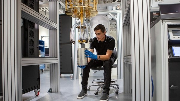 一位亚马逊云科技量子硬件工程师正在操作稀释制冷机器。稀释制冷机可以将量子处理器冷却至比外太空环境更低的温度。