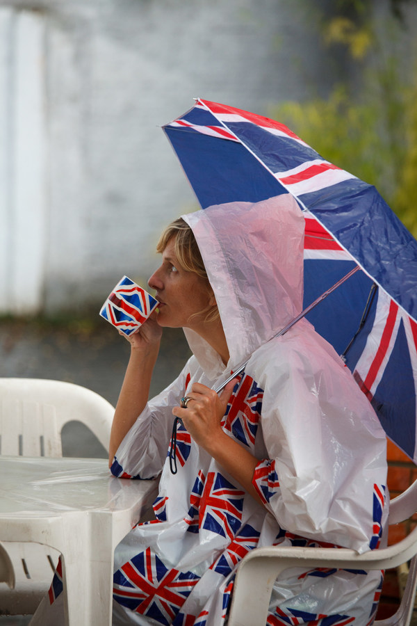 Patriotic clothed British lady drinking tea during wet weather - source Getty Images