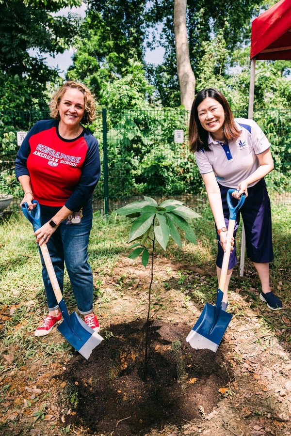 Ms. Hany Soh and Dr. Jennifer Sparrow plant a tree at the newly opened Woodgrove/Singapore American School community garden