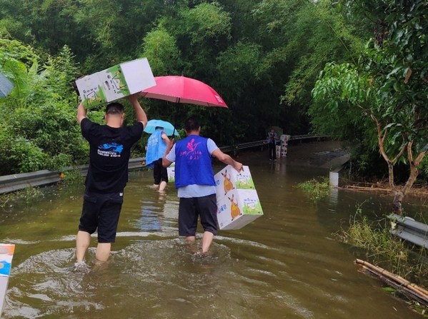 志愿者涉水将夏季温暖包送到梧州儒岩村受灾的孩子们手中