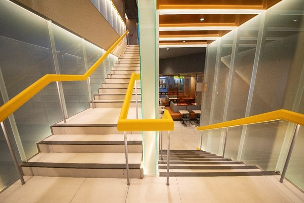 店內半透明的樓梯連接上下兩層，梯底以橙色鏡面裝飾，營造明亮活力的氛圍。