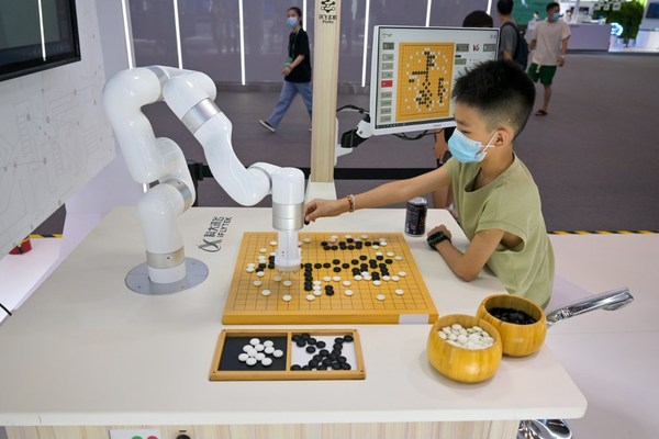 A boy plays Go with a robot in the exhibition hall of SCE 2022, on 21st August 2022, Chongqing, China. (photo/ Ganxi Yi)