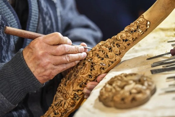 A craftsman makes woodcarving using wood from Chinese pistache tree.