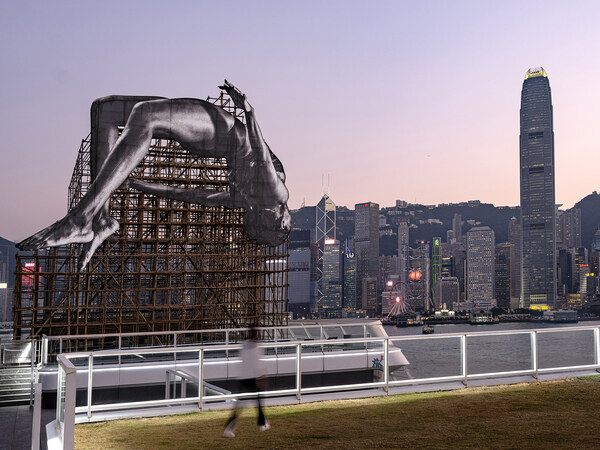 “GIANTS: Rising Up” Public Art Installation at Harbour City Shopping Mall depicts a gigantic high jumper floating in mid-air adjacent to Hong Kong’s iconic Victoria Harbour