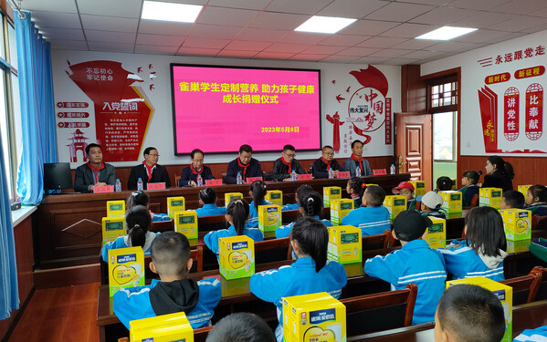 县领导薛强向礼县永兴镇中心小学的学生们分发儿童奶粉