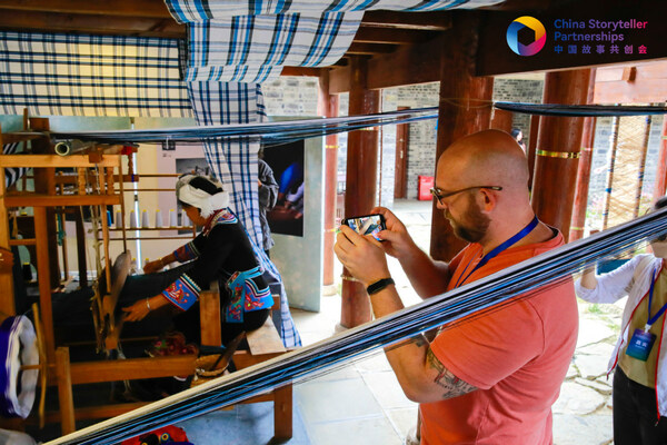 The author takes photos of traditional Bouyei ethnic weaving in Wanfenglin Scenic Area. [Photo provided to chinadaily.com.cn]