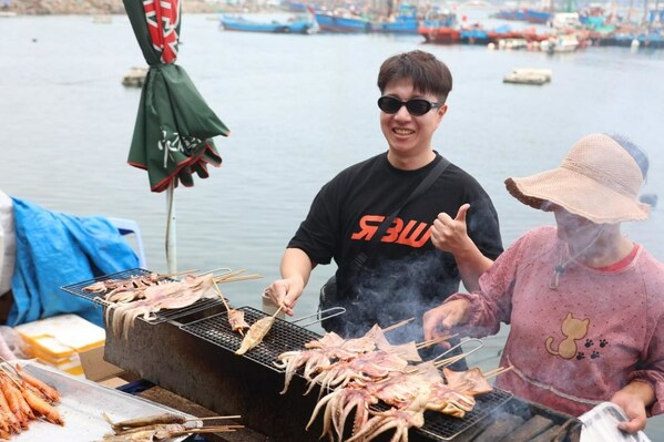 Korean travel Vlogger Kim JunBum (left) is trying the seafood barbecue Photo by Wang Wen