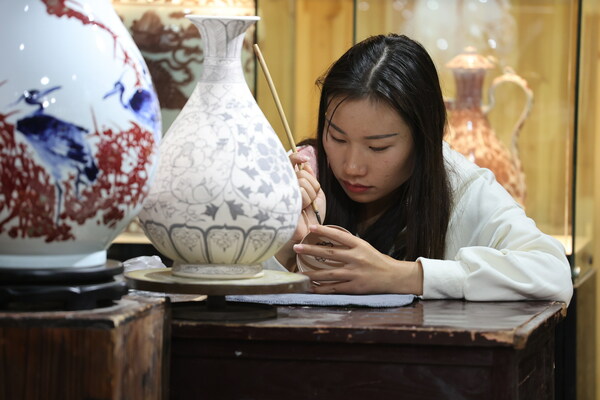 A woman paints porcelain at a ceramic workshop in Taoyangli imperial kiln historical block in Jingdezhen, Jiangxi province. Li Jin / China Daily