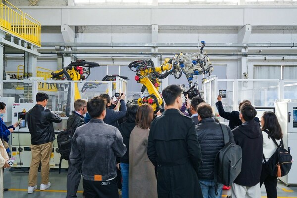 Observers watch industrial robots working based on instructions wirelessly transmitted at high speeds via 5G-Advanced indoor base stations