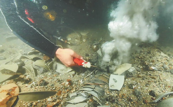 Sediment is removed from the relics at the shipwreck site. [Photo provided to China Daily]