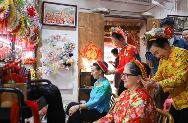 Photo shows that foreign tourists are experiencing Xunpu flowery headwear, a national intangible heritage in Xunpu Village.