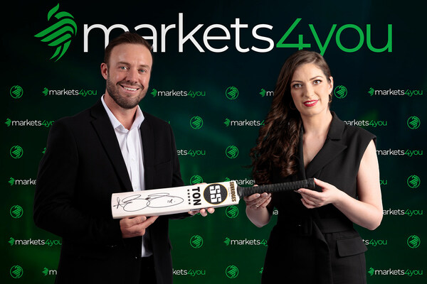 Bà Marina Strausa, CEO của Markets4you, đang giữ một cây gậy cricket có chữ ký bên cạnh ông AB de Villiers.