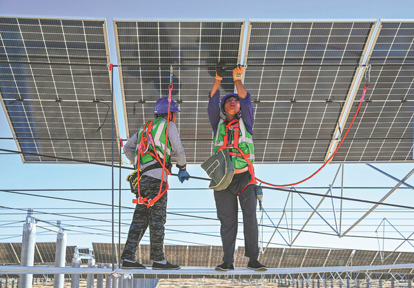 Workers install photovoltaic panels as part of a desertification control project in the Kubuqi Desert in North China's Inner Mongolia autonomous region in July 2023. LIU LEI/XINHUA