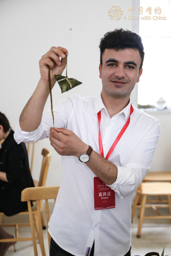 Mohammad Hashem Mohammadi, a Shanghai-based Afghan content creator, poses for photo holding a& zongzi& in Weihai, East China’s Shandong province, on June 7, 2024. [Photo provided to chinadaily.com.cn]