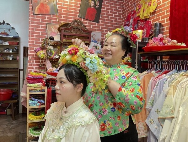 Photo shows a villager pins a flowery headwear for a tourist at Xunpu Village of Quanzhou City, southeast China