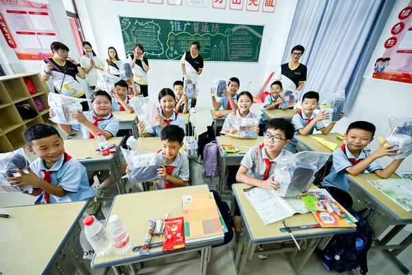 Sands China team members tour the newly constructed Aoyi Primary School Tuesday and pass out gift packs, including school stationery for the new scholastic year and sports equipment for the school.