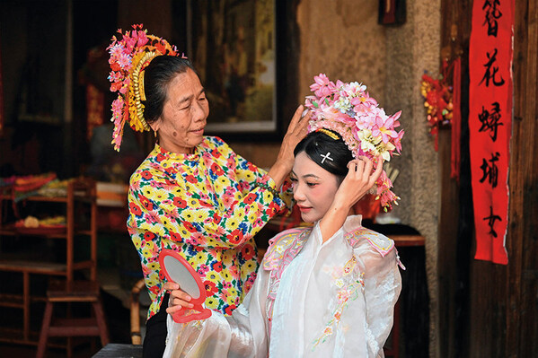 A tourist (right) is wearing flowery headwear at Xunpu Village of Quanzhou City, southeast China's Fujian Province, Aug. 27, 2025. (Provided by Zhou Yi) A tourist (right) is wearing flowery headwear at Xunpu Village of Quanzhou City, southeast China's Fujian Province, Aug. 27, 2025. (Provided by Zhou Yi)