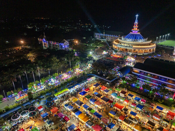 Aerial view of the Sakon Nakhon Christmas Star Parade showing illuminated star processions, festive market stalls, and the Cathedral of St Michael the Archangel during the annual celebration in Tha Rae, Sakon Nakhon.